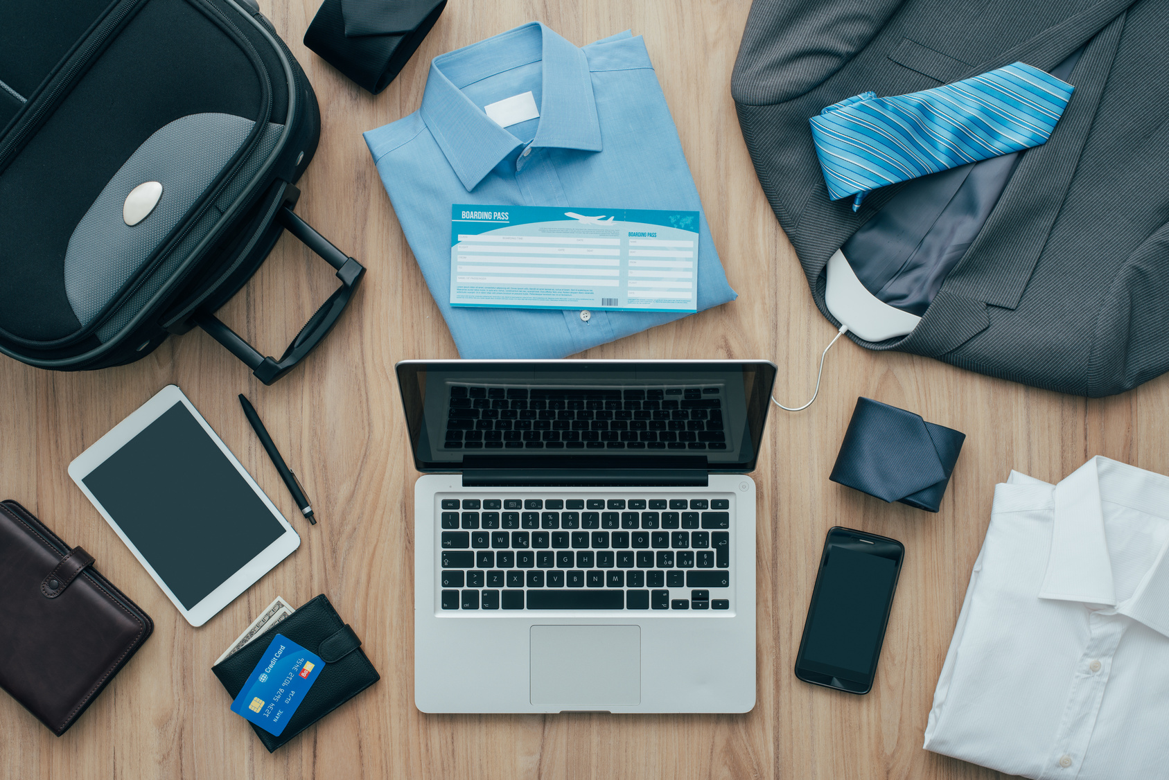 How to pack for a business trip: all items that needs to be packed, a bag and a laptop on a desktop, travel concept